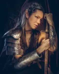 Fae woman in armor leaning on sword.